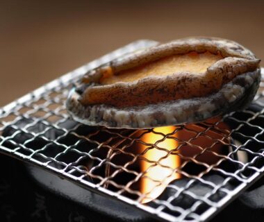 Abalone grilling over charcoal flame on a small metal grill at Seizan Yamato ryokan in Shizuoka
