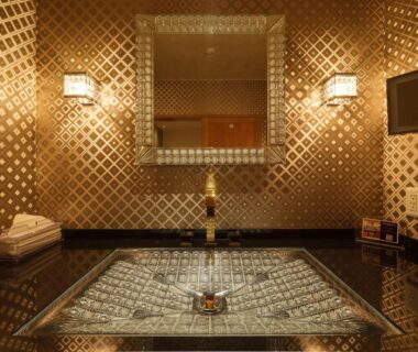 Sunken mosaic-tiled indoor bath with mirror and wall sconces in Sekitaitei Ishida, Nagano
