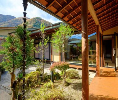 Wooden veranda overlooking a small garden and shoji screens with mountain backdrop at Sekitaitei Ishida, Nagano