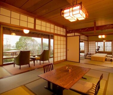 Traditional tatami room with low table, chairs, shoji screens, futon area and garden view at Sekitei, Hiroshima