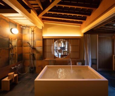 In-room wooden soaking tub, shoji screen, exposed beams, warm lighting at Sekitei, Hiroshima