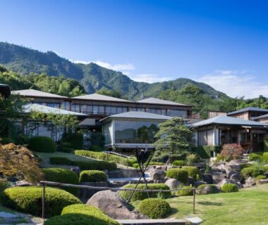 Landscaped Japanese garden and ryokan buildings at Sekitei with mountain backdrop in Hiroshima
