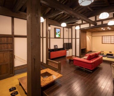 Interior lounge with exposed wooden beams, shoji screens, tatami seating and sofa at Sen-no-Mori in Kumamoto, Kyūshū