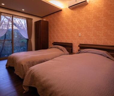 Twin room with two beds, wood floor, soft lighting and large window at Sen-no-Mori, Kumamoto, Kyūshū