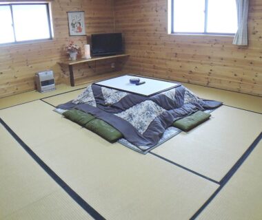Traditional tatami room with kotatsu, floor cushions, wooden walls and windows at Sendaiya ryokan in Gifu