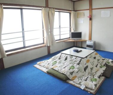 Kotatsu with quilt and floor cushions in a Sendaiya guest room, windows and TV, Gifu, Chūbu, Japan