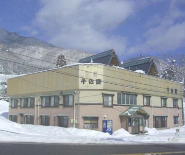 Snow-covered exterior of Sendaiya ryokan with mountain backdrop in Chubu, Gifu, Japan