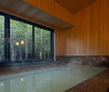 Steaming indoor onsen bath at Sengokubara COCON with wooden walls and garden view in Kanagawa