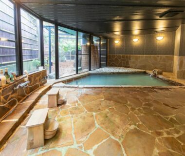 Indoor stone onsen bath with stools and washing stations at Sengokuhara Hisanoha Kanagawa