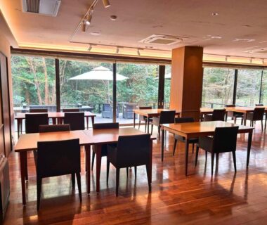 Spacious dining area with wooden floors, tables and chairs facing garden through large glass windows at Sengokuhara Hisanoha