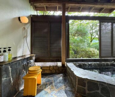 Stone onsen bath with wooden stools and garden view at Sengokuhara Shinanoki Ichinoyu, Kanagawa