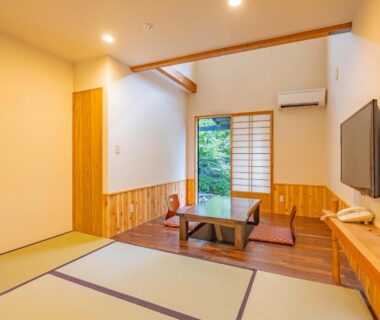 Tatami room with low table, zabuton cushions and shoji door opening to garden at Sengokuhara Shinanoki Ichinoyu