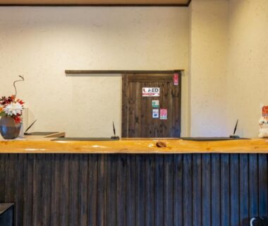 Reception counter with wooden front, floral arrangement and decorative figurine at Sengokuhara Shinanoki Ichinoyu, Kanagawa