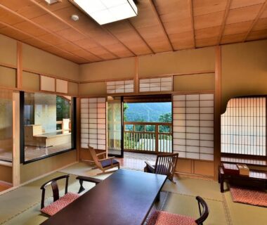 Tatami room with low table, shoji screens and balcony overlooking mountains at Senjukaku in Nagano