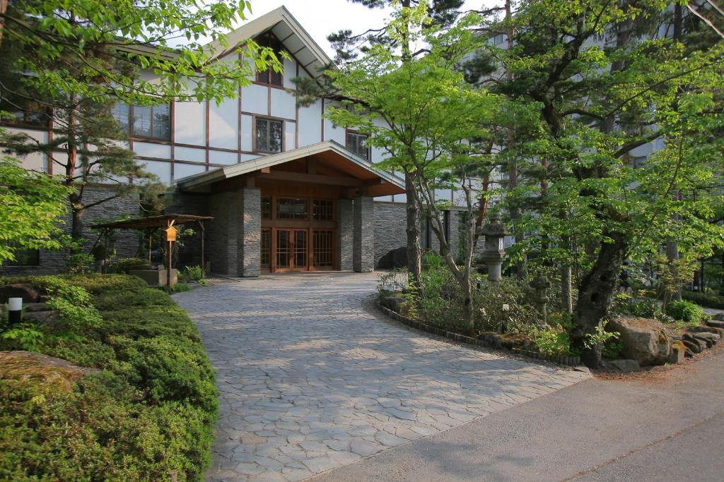 Ryokan entrance Senjukaku Nagano Stone driveway leading to Senjukaku wooden entrance surrounded by evergreen trees and traditional exterior in Nagano, Chūbu Japan
