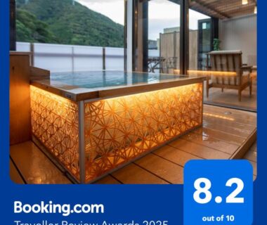 Illuminated wooden bathing tub with decorative panel, glass terrace doors and mountain view at Senkei ryokan, Kanagawa