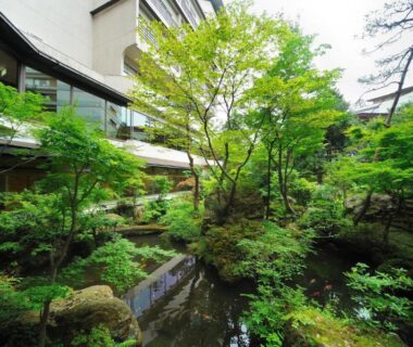Lush moss garden with reflecting pond, stone accents and surrounding hotel wings at Senkeien Tsukioka Hotel Yamagata