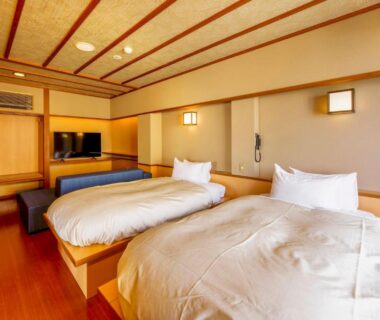 Twin beds on raised wooden platform with shoji screens and low seating in Senoumi ryokan, Shizuoka