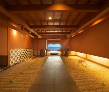 Long wooden corridor with tatami flooring and warm lighting leading to a distant opening at Senoumi, Shizuoka