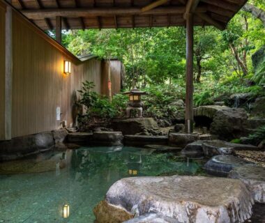 Stone outdoor onsen with covered roof and surrounding garden at Senpokaku in Mie, Kansai