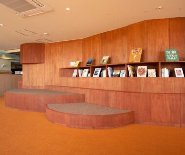 Spacious wood-paneled lobby with tiered seating and book display at Senpokaku in Mie