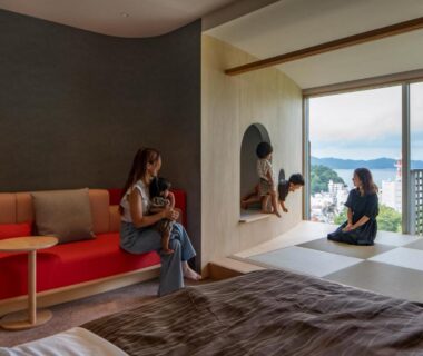 Tatami alcove and red sofa with two guests enjoying balcony view toward distant landscape