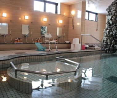 Tiled indoor communal bath with shower stations and rock water feature at Senshoen, Hokkaidō, Japan