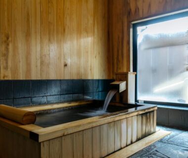 Indoor wooden soaking tub with spout and window at Sensui Ryokan Hyogo Kansai