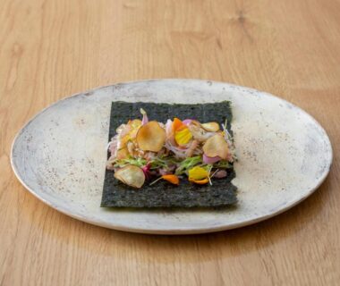 Nori sheet topped with mixed garnishes and edible flowers on ceramic plate at Sensui Ryokan Hyōgo