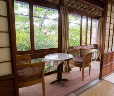 Engawa seating with round table and chairs overlooking leafy garden at Senzairou, Gifu