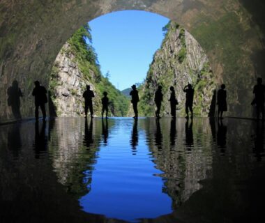 Silhouetted visitors in tunnel reflected on still water at Setoguchi, Chūbu, Niigata