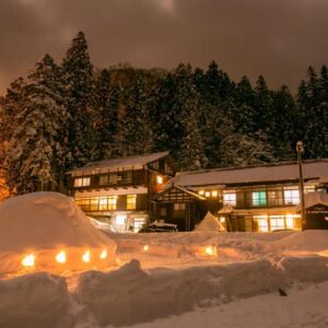Traditional ryokan lit at night amid snow mounds and lanterns, Setoguchi, Niigata, Chūbu, Japan