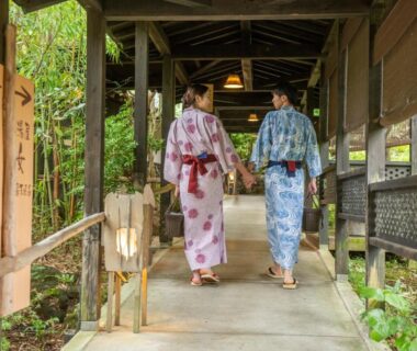 Two guests in yukata walking along a wooded covered corridor at Setsugetsuka ryokan in Kanagawa