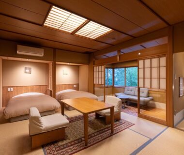 Japanese tatami room with beds, low table, shoji screens and seating area at Shaga-no-Sato Yumeya in Niigata