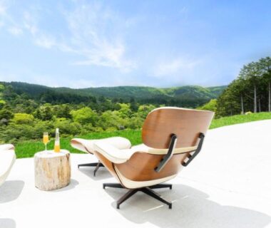 Sunlit terrace with modern lounge chairs overlooking lush hills and woodland at Shelter Garden Nikko, Tochigi