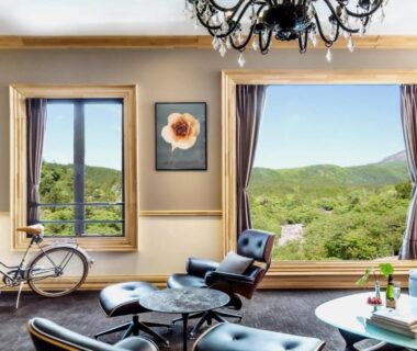 Bright lounge with leather chairs and large windows framing green hills at Shelter Garden Nikko, Tochigi