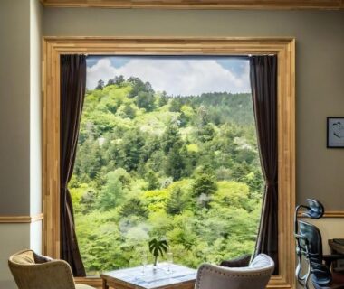 Bedroom seating area with large window overlooking lush green hillside at Shelter Garden Nikko, Tochigi