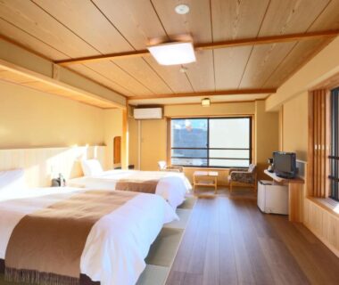 Spacious tatami-floored twin room with low beds, shoji screens and large windows at Shibu Hotel Nagano