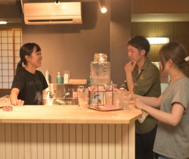 Guests chatting with staff at wooden reception counter with shoji screens in Shibu Onsen KADOYA, Nagano