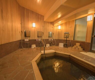 Indoor wooden onsen bath with stools and hand showers at Shibu Onsen KADOYA, Nagano