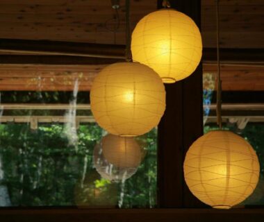 Round paper lanterns above wooden interior, window showing greenery at Shibu Tatunokan in Nagano