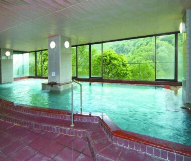 Spacious tiled indoor onsen bath with panoramic windows overlooking forest at Shiga Kogen Hotel Shiga Sunvalley, Nagano, Chūbu, Japan