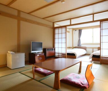 Traditional tatami room with low table, futon area and shoji screens at Shiga Palace Hotel, Nagano, Chūbu Japan