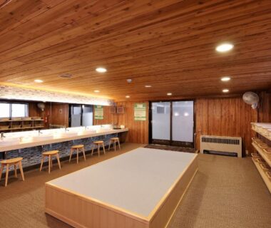 Wood-paneled communal changing room with benches and sinks at Shiga Park Hotel in Nagano, Chūbu