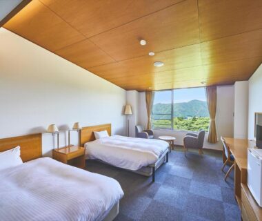 Spacious twin room with two beds, wooden ceiling, desk, window with green hillside view at Shiki Resort Hakone Style