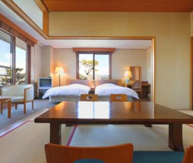 Tatami-floored room with low table, twin beds, shoji screens and seating area at Shiki Resort Hida Takayamaso in Gifu
