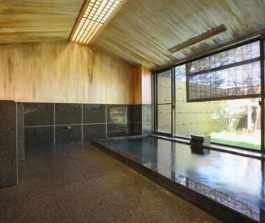 Stone-lined indoor onsen with garden-facing windows at Shiki Resort Hida Takayamaso, Gifu prefecture