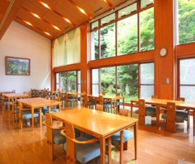 Spacious wooden dining room with large windows overlooking verdant garden at Shiki Resort Hida Takayamaso in Gifu
