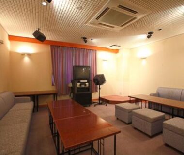 Lounge with karaoke setup, cushioned benches and low wooden tables at Shiki Resort Hida Takayamaso, Gifu