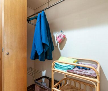 Small changing area with hanging jacket, wall hairdryer and rattan shelf holding folded towels at Shikino Mori, Kumamoto
